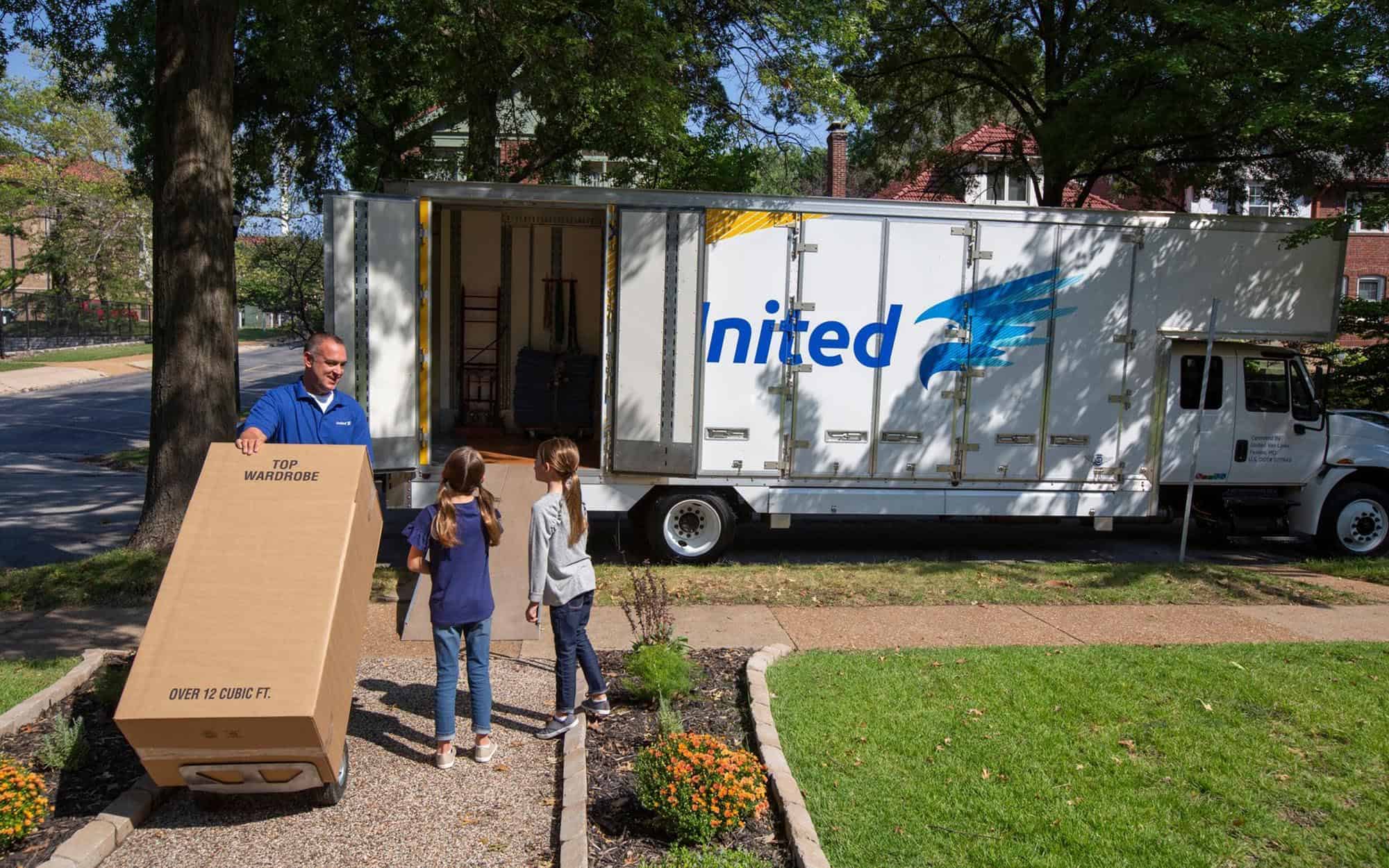 Moving professional talking to two children in front of United branded moving truck
