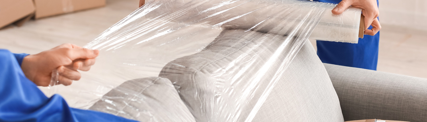 Side view of two movers wrapping a couch