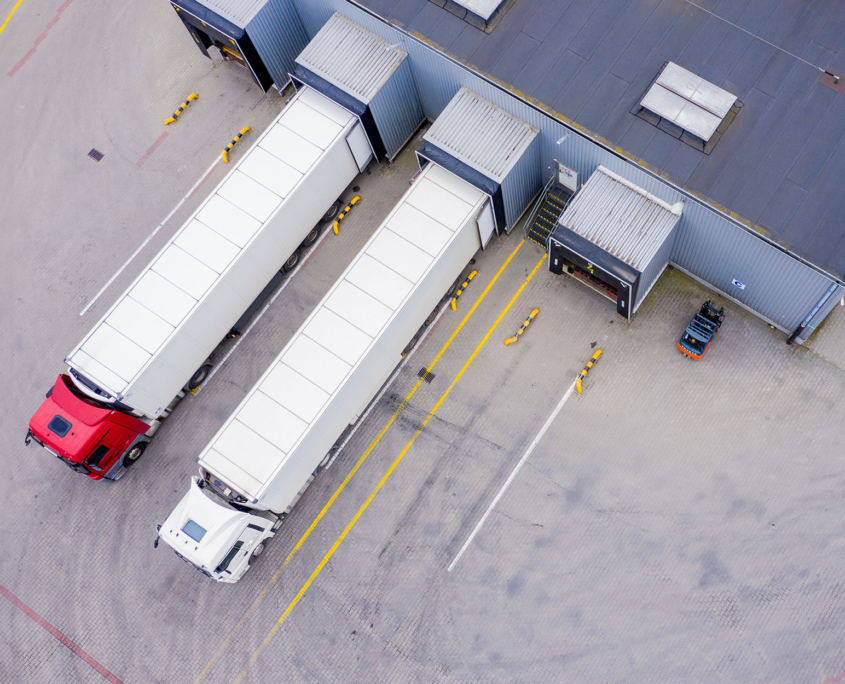 Top-down view of two trucks being loaded or unloaded at warehouse dock