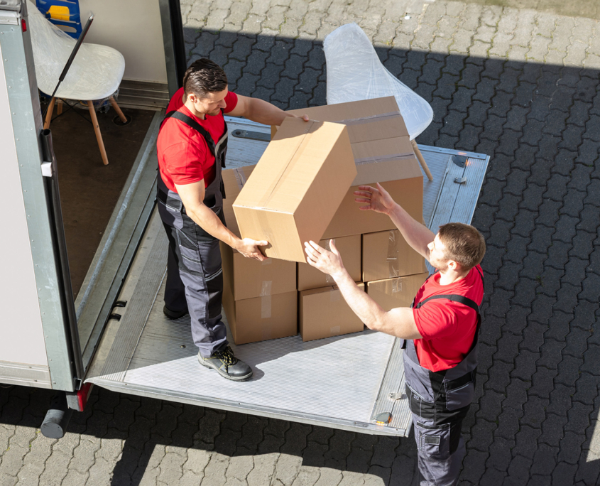 Two male moving staff unloading boxes from moving truck