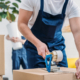 Cropped view of mover wrapping cardboard box with scotch tape in apartment