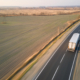 Aerial view of blurred fast moving semi-truck with cargo trailer driving on highway