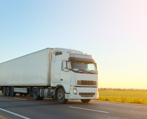 Semi-truck with cargo trailer driving on highway hauling goods in evening