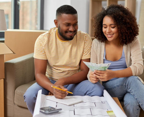 mortgage, moving and real estate concept - happy african american couple with blueprint and calculator counting money
