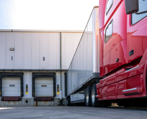 Red modern American semi truck parked at the docks