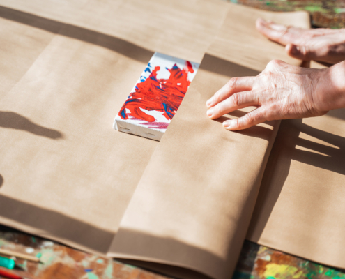 Woman wrapping her drawing at the paper while making present for somebody