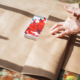 Woman wrapping her drawing at the paper while making present for somebody